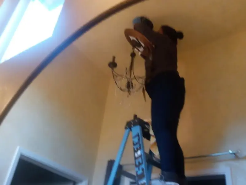 Electrician installing a chandelier in a Plaquemine residence